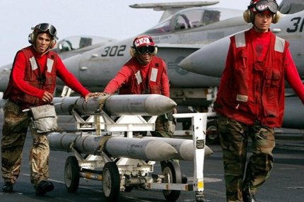 Военные транспортируют ракеты AIM-120 AMRAAM на палубе авианосца USS Kitty Hawk 10 марта 2003 года