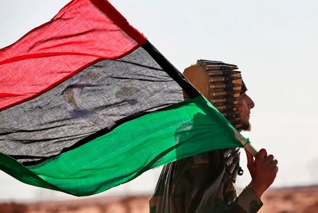 Мужчина несёт флаг Ливии