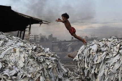 Ребенок прыгает через мусор в Хазарибахе, Дакка, Бангладеш, 9 октября 2012 года.