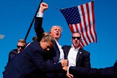 Трамп поднимает вверх кулак во время покушения на него