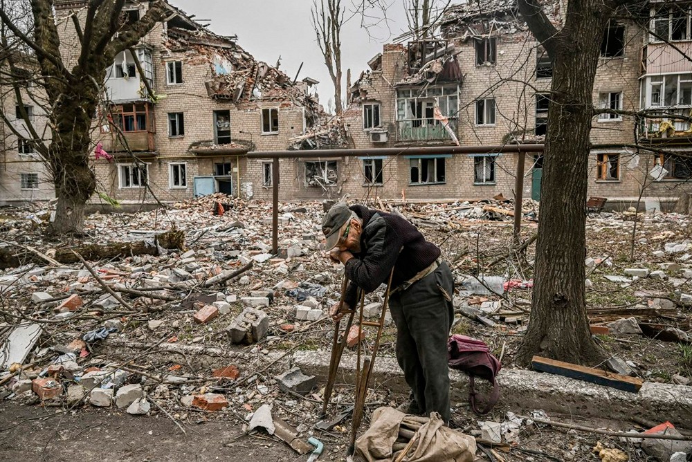 Пенсионер возле разрушенного войной дома  
