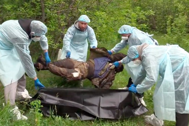 Пленные украинские военные собирают тела погибших сослуживцев