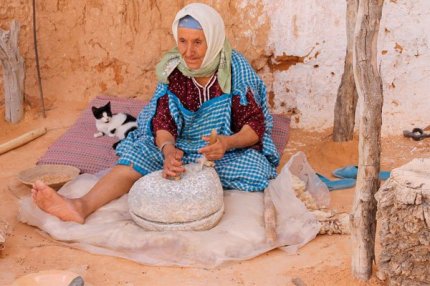 Пожилая тунисская женщина готовит еду