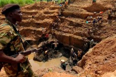 Вооруженный солдат контролирует добычу кобальта детьми в Конго
